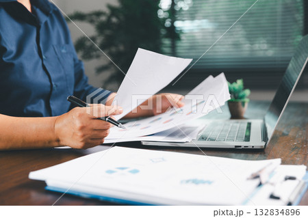 Office businesswoman hand to operate calculator analyzing financial data, counting costs on desk. accounting, financial analysis for business budget planning, calculation support, finance management. Office businesswoman hand to operate calculator analyzing financial data, counting costs on desk. accounting, financial analysis for business budget planning, calculation support, finance management. 132834896