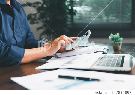 Office businesswoman hand to operate calculator analyzing financial data, counting costs on desk. accounting, financial analysis for business budget planning, calculation support, finance management. 132834897