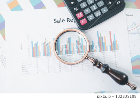 Magnifying glass with calculator and pen on financial reports with charts, graphs at office desk. Concept of business analysis, accounting audit, financial accuracy, transparency, corporate strategy. Magnifying glass with calculator and pen on financial reports with charts, graphs at office desk. Concept of business analysis, accounting audit, financial accuracy, transparency, corporate strategy. 132835189