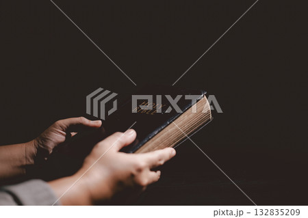 Hands clasped in prayer over the Holy Bible, symbolizing faith, devotion, Christianity, hope and spiritual strength through God Word, worship, meditation and encouragement. 132835209