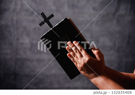 Bible in hand, christian lifts prayer in worship, holding firmly to holy concept of faith, hope and deep belief guides their spiritual life. Hands together in prayer to God along with bible Bible in hand, christian lifts prayer in worship, holding firmly to holy concept of faith, hope and deep belief guides their spiritual life. Hands together in prayer to God along with bible 132835409