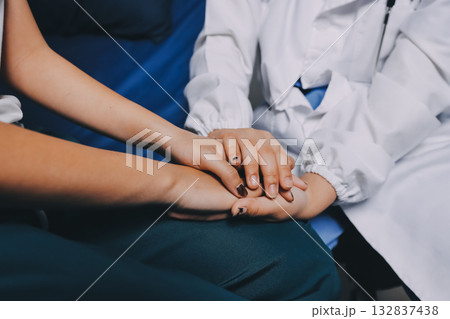 Doctor giving hope. Close up shot of young female physician leaning forward to smiling elderly lady patient holding her hand in palms. Woman caretaker in white coat supporting encouraging old person Doctor giving hope. Close up shot of young female physician leaning forward to smiling elderly lady patient holding her hand in palms. Woman caretaker in white coat supporting encouraging old person 132837438