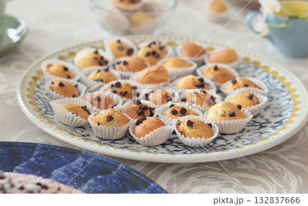 Mini chocolate cupcakes on patterned ceramic plate. Holidays and lifestyle. Food on table covered with tablecloth. Mini chocolate cupcakes on patterned ceramic plate. Holidays and lifestyle. Food on table covered with tablecloth. 132837666