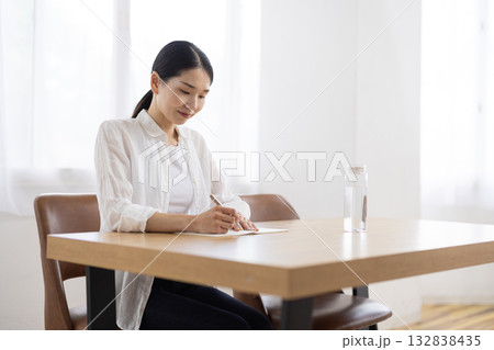 テーブルでノートにメモをとるミドル女性 132838435
