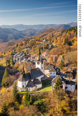 The Spania Dolina village in Slovakia, Europe. Picturesque village nestled among rolling hills and autumn foliage, with a prominent church steeple, creating a serene landscape. 132838581