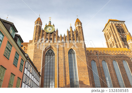 St. Mary's Church in Gdansk, a city on the Baltic coast of northern Poland, Europe. Majestic old church with intricate brickwork, clock, tall spires against a light sky. St. Mary's Church in Gdansk, a city on the Baltic coast of northern Poland, Europe. Majestic old church with intricate brickwork, clock, tall spires against a light sky. 132838585