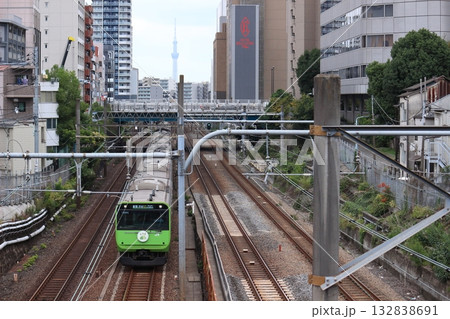 ビルの谷間をゆく山手線環状運転100周年車両(2025年) 132838691