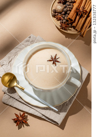 Traditional Indian masala chai tea with milk and spices in a cup on a beige background 132838777