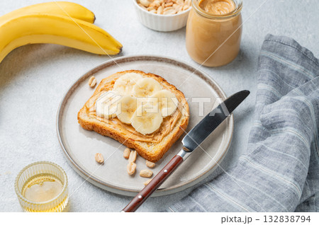 Peanut butter toast and banana in a plate on a light background with nuts Peanut butter toast and banana in a plate on a light background with nuts 132838794