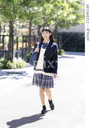 スクールバッグを肩にかけて歩く笑顔の女子高校生　 132840189
