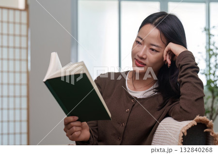 Focused Reading. Woman deeply engaged in a book while relaxing at home. 132840268
