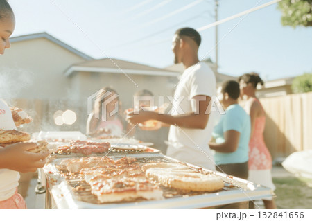 Family enjoying backyard barbecue during summer gathering with pastel decorations 132841656