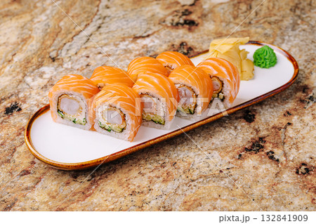 Sushi platter featuring salmon rolls with ginger and wasabi on a marble table 132841909