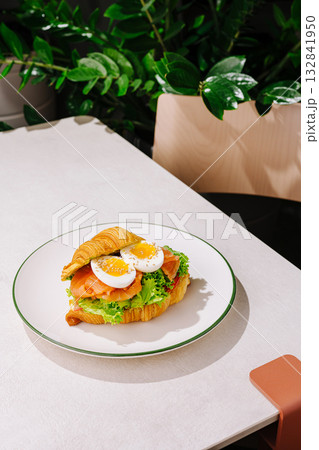 Delicious croissant sandwich with fresh ingredients on a white plate 132841950