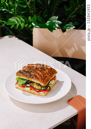 Delicious sandwich on a plate in a modern cafe setting with greenery Delicious sandwich on a plate in a modern cafe setting with greenery 132841953