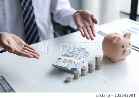 A person with money, coins, and a piggy bank on a table. Concept of saving money. 132842001