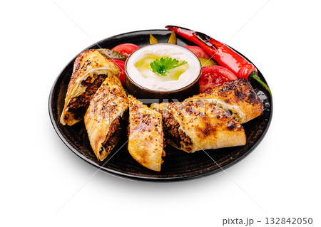Savory meat rolls with fresh vegetables and yogurt dip on a black plate Savory meat rolls with fresh vegetables and yogurt dip on a black plate 132842050
