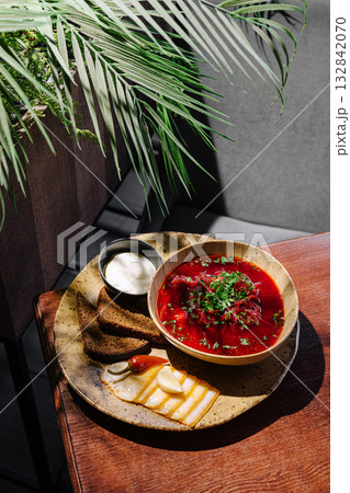Delicious beet soup served with bread and cheese on a wooden table Delicious beet soup served with bread and cheese on a wooden table 132842070