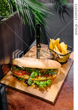 Fresh sandwich and crispy fries served on a wooden board in a cafe setting 132842072