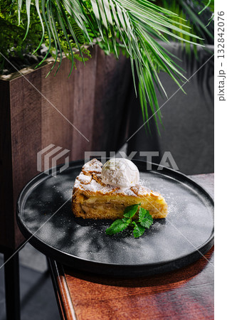 Enjoying a slice of delicious apple pie with ice cream on a table Enjoying a slice of delicious apple pie with ice cream on a table 132842076