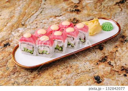 Sushi rolls served on a white plate with garnishes and a colorful background 132842077