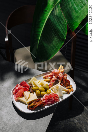 Assorted cheese and charcuterie platter with greens in a cozy setting Assorted cheese and charcuterie platter with greens in a cozy setting 132842120