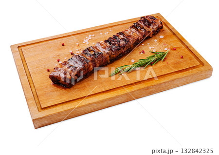 Grilled steak served on a wooden cutting board with fresh herbs 132842325