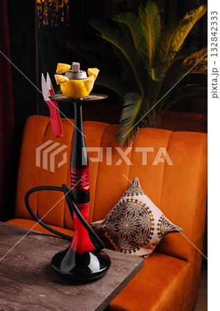 Unique hookah setup with fruit and decorative cushion in cozy lounge 132842333