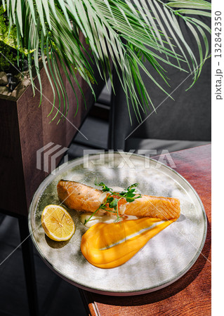 Delicious salmon dish served with lemon and mango puree in a modern setting 132842350