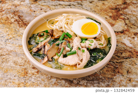 Ramen bowl with chicken, egg, and veggies on a granite counter Ramen bowl with chicken, egg, and veggies on a granite counter 132842459