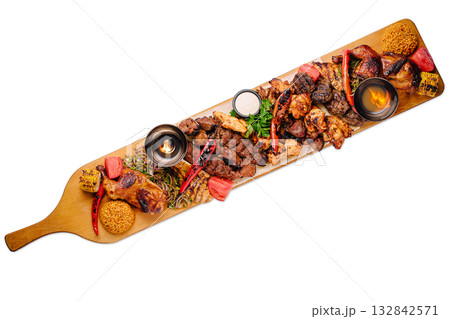 Delicious variety of grilled meats served on large wooden platter at restaurant Delicious variety of grilled meats served on large wooden platter at restaurant 132842571