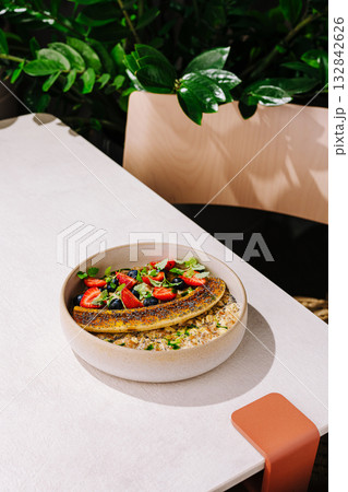 Enjoying a healthy bowl of oatmeal topped with fresh fruit in a sunny cafe Enjoying a healthy bowl of oatmeal topped with fresh fruit in a sunny cafe 132842626