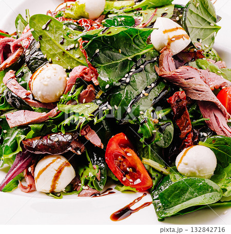 Fresh salad with greens, mozzarella, and roasted meat served in a restaurant Fresh salad with greens, mozzarella, and roasted meat served in a restaurant 132842716
