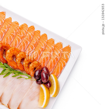 Seafood platter with salmon, shrimp, and lemon garnishes on table 132842853