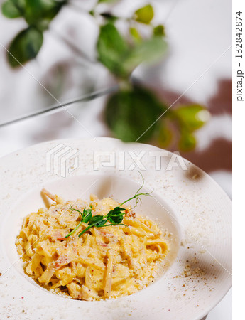 Creamy pasta dish with herbs served in stylish restaurant setting 132842874