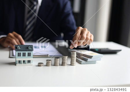 Investing in Real Estate, Real estate agent or investor calculating, planning, analyzing financial data for property investment. Themes of saving, investing, financial aspects of purchasing a home. Investing in Real Estate, Real estate agent or investor calculating, planning, analyzing financial data for property investment. Themes of saving, investing, financial aspects of purchasing a home. 132843491