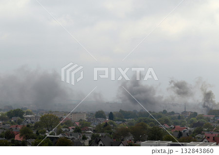 A stark, desolate landscape over a city in Ukraine. Thick, dark smoke billows into the grey sky from a major fire. Fire in Ukraine. Ukraine war smoke city fire A stark, desolate landscape over a city in Ukraine. Thick, dark smoke billows into the grey sky from a major fire. Fire in Ukraine. Ukraine war smoke city fire 132843860