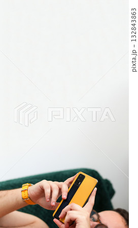 vertical shot capturing a man engaged in active smartphone use. online shopping or reviewing an important message on phone. Vertical banner for reel or stories vertical shot capturing a man engaged in active smartphone use. online shopping or reviewing an important message on phone. Vertical banner for reel or stories 132843863