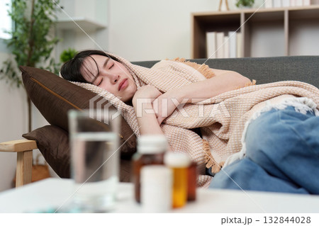 Health Awareness: Young woman resting on couch with blanket 132844028