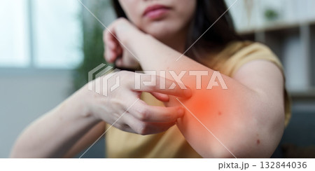 Health Awareness: Young woman experiencing arm pain at home Health Awareness: Young woman experiencing arm pain at home 132844036