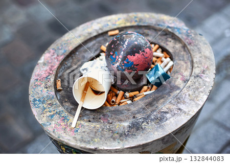 Cigarette butts and other waste in an ashtray 132844083