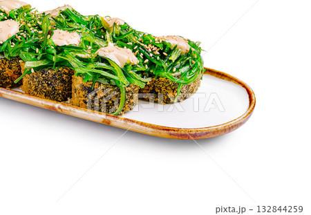 Delicious sushi rolls topped with vibrant green seaweed salad for lunch 132844259