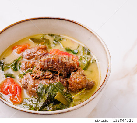 Savory beef stew with fresh herbs and vegetables in a rustic bowl 132844320