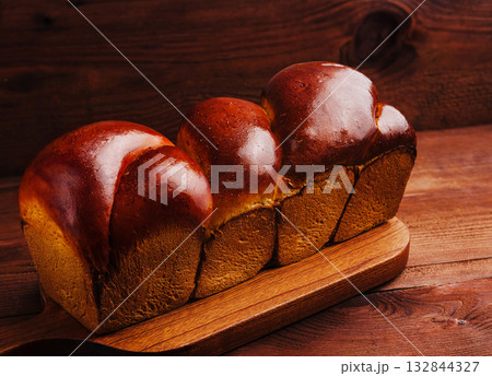 Freshly baked bread loaves on a wooden cutting board in warm lighting 132844327