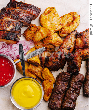 Delicious grilled meats with sauces and sides served on a platter Delicious grilled meats with sauces and sides served on a platter 132844361