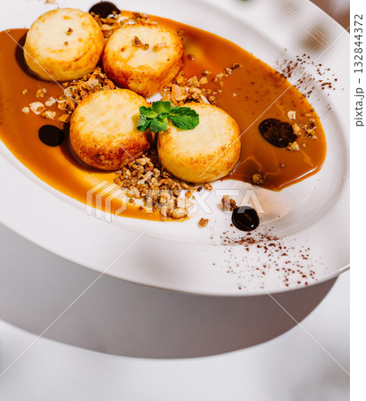 Dessert plate featuring round sweet cottage cheese pancakes with caramel sauce and nuts 132844372