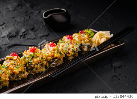 Delicious sushi rolls on a black plate with wasabi and ginger garnish Delicious sushi rolls on a black plate with wasabi and ginger garnish 132844430
