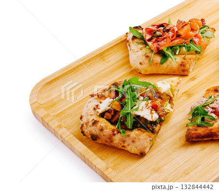 Delicious flatbreads topped with fresh ingredients on a wooden board 132844442