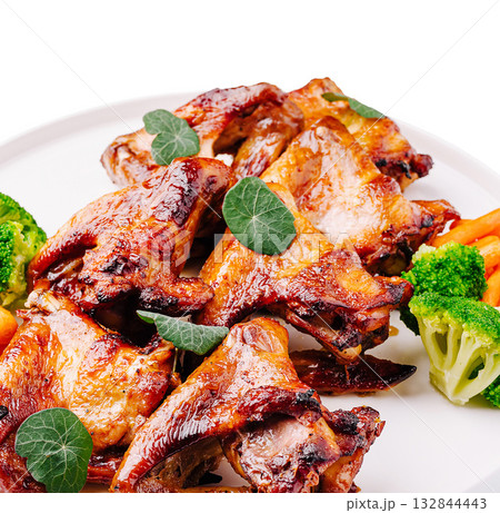 Grilled chicken wings garnished with herbs and fresh vegetables for a meal Grilled chicken wings garnished with herbs and fresh vegetables for a meal 132844443