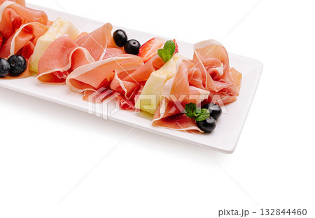 Delicious platter of cured meats and fresh fruits served elegantly Delicious platter of cured meats and fresh fruits served elegantly 132844460